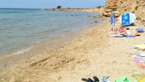 A sandy beach with a clear view of the sea, a few people relaxing, and a cliff in the background. - Apartments Mirjana Privlaka / A1 Two Bedrooms (Privlaka)