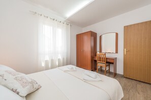 Ein Hotelzimmer mit einem Bett, einem Holztisch, einem Stuhl, einem Schrank und einem Spiegel.