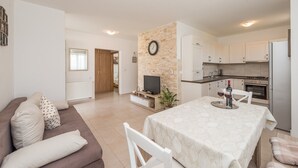 A modern apartment with a living room, dining area, kitchen, and a visible clock on the wall. - Apartments Mirjana Privlaka / A1 Two Bedrooms (Privlaka)