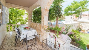 A covered outdoor dining area with stone arches, a table with chairs, and potted plants. - Apartments Mirjana Privlaka / A1 Two Bedrooms (Privlaka)