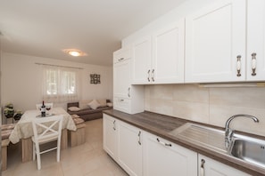 A compact kitchen with white cabinets, a wooden countertop, and a sink.