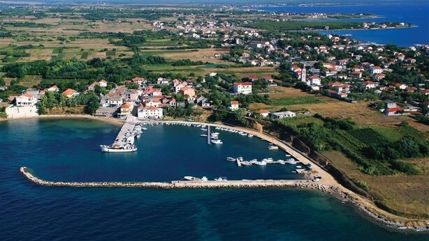 An aerial view of a coastal town with a marina, houses, and a prominent building with a tower. - Apartments Mirjana Privlaka / A1 Two Bedrooms (Privlaka)