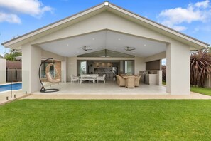 Una casa moderna con veranda coperta, piscina e prato curato.