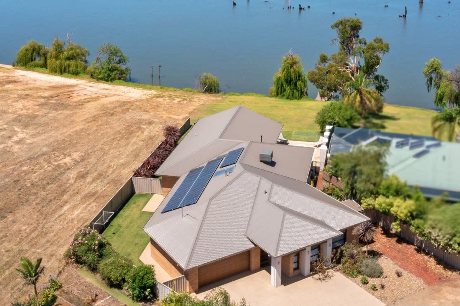 A two-story house with a sloped roof, solar panels, and a large yard with a swimming pool.