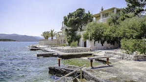 A coastal building with a stone facade, a balcony, and a view of the sea. - Apartments Krstičević (Slivno)
