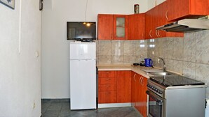 Eine kleine Küche mit Kühlschrank, Herd, Mikrowelle und Spüle.