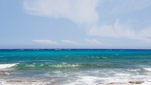 Ein Strand mit klarem türkisblauem Wasser und einer felsigen Küste.