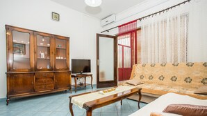 A living room with a wooden cabinet, a television, a sofa, and a coffee table. - Apartments Divna Tomas (Omis)