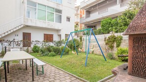 A courtyard with a swing set, a picnic table, and a stone fountain. - Apartments Divna Tomas (Omis)