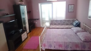 Ein Schlafzimmer mit einem Bett, einem Fernseher, einem Kleiderschrank und einem Fenster.
