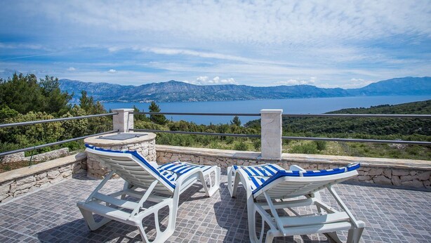 A terrace with two white lounge chairs with blue cushions, overlooking a scenic view of mountains and a lake. - Holiday House Domina (Postira)