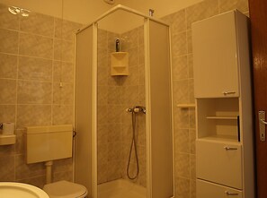 A bathroom with a toilet, a shower enclosure, and a cabinet. - Apartments Janja Postira (Postira)