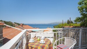 Un balcon avec une table dressée pour deux personnes, offrant une vue sur la côte.