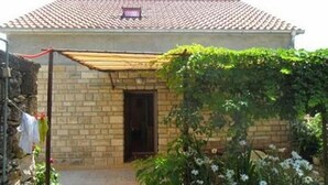 Un bâtiment d’un seul étage, avec un toit recouvert de tuiles, une façade en briques et une petite porte.