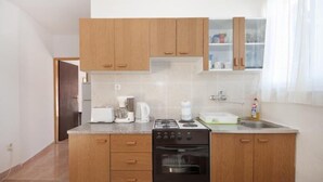 Une cuisine compacte avec des meubles de rangement en bois, une cuisinière à gaz, une machine à café et un évier.