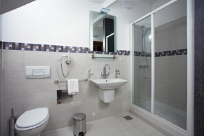 A modern bathroom with a toilet, sink, and glass-enclosed shower. - Apartments Vila Marija (Supetar)