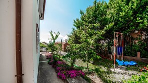 A narrow pathway leading to a building with a white exterior and a red door. - Apartments Jasko / Two Bedroom Jasko 2 (Rab)