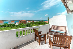 Ein Balkon mit Holzmöbeln und Blick auf das Meer und die Gebäude.