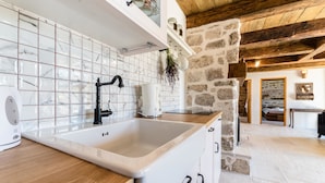Una cocina con un lavabo blanco, encimera de madera y pared de piedra.