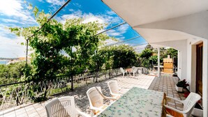 Un patio esterno con tavolo e sedie, circondato da un recinto bianco e alberi.