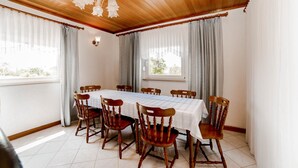 Una sala da pranzo con soffitto in legno, un tavolo apparecchiato per sei persone e tende alle finestre.