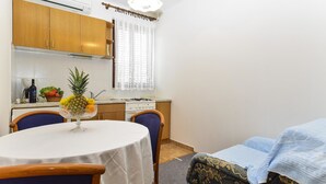 Una cocina compacta con armarios de madera, una mesa de comedor con sillas y un pequeño rincón de kitchenette.