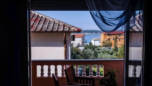 A balcony with a view of buildings and a body of water. - Apartments Jasko (Rab)