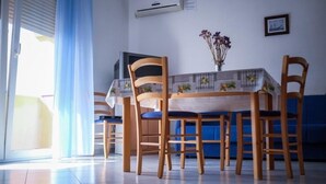 A dining area with a table set for four, surrounded by wooden chairs with blue cushions. - Apartments Jasko (Rab)