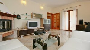 Ein modernes Wohnzimmer mit Flachbildfernseher, Glastisch und Kamin.