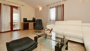 Ein modernes Wohnzimmer mit einem Glastisch, einer schwarzen Ledersofa, einem weißen Sofa, einem schwarzen Ledersessel und einem kleinen Schrank.