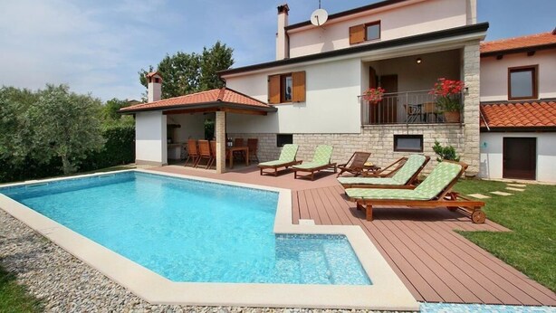 Ein zweistöckiges Haus mit Schwimmbad, Sitzgelegenheiten im Freien und einem Balkon.