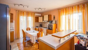 A compact kitchen with a dining area, featuring a refrigerator, stove, oven, and a small island with a sink. - Apartment Zoki i Goga / Two Bedroom (Okrug)