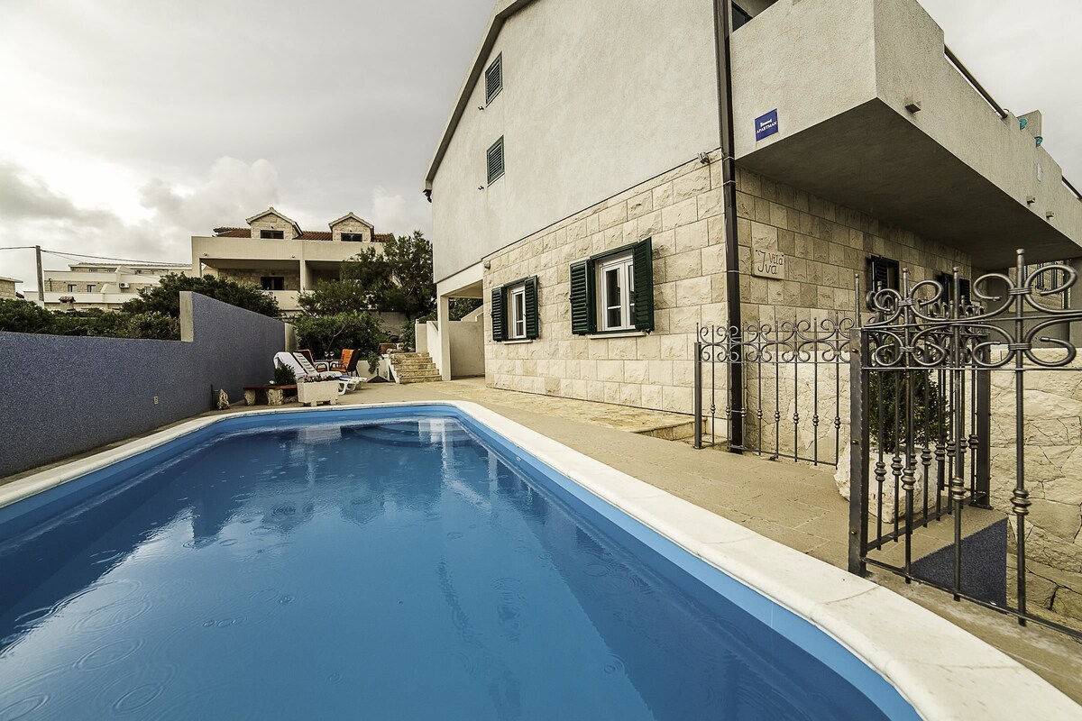 Une piscine avec un mur en pierre et un portail en métal.