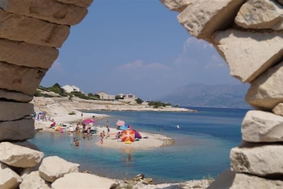 Une plage avec une eau d’un bleu limpide, des gens qui se baignent et des parasols.