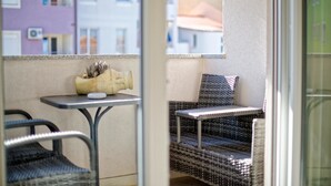 A balcony with wicker furniture, a small table, and a decorative vase.