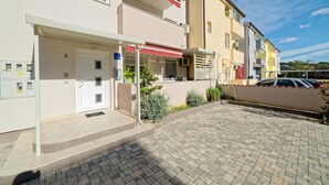 A multi-story residential building with a paved driveway and a small garden area.