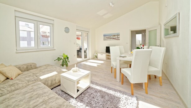 A modern living room with a sofa, coffee table, and dining area with chairs.