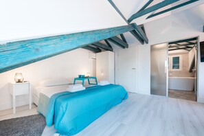 A bedroom with a bed, bedside table, and a nightstand. There is a door leading to a bathroom. - EuroAdria Residence (Dubrovnik)