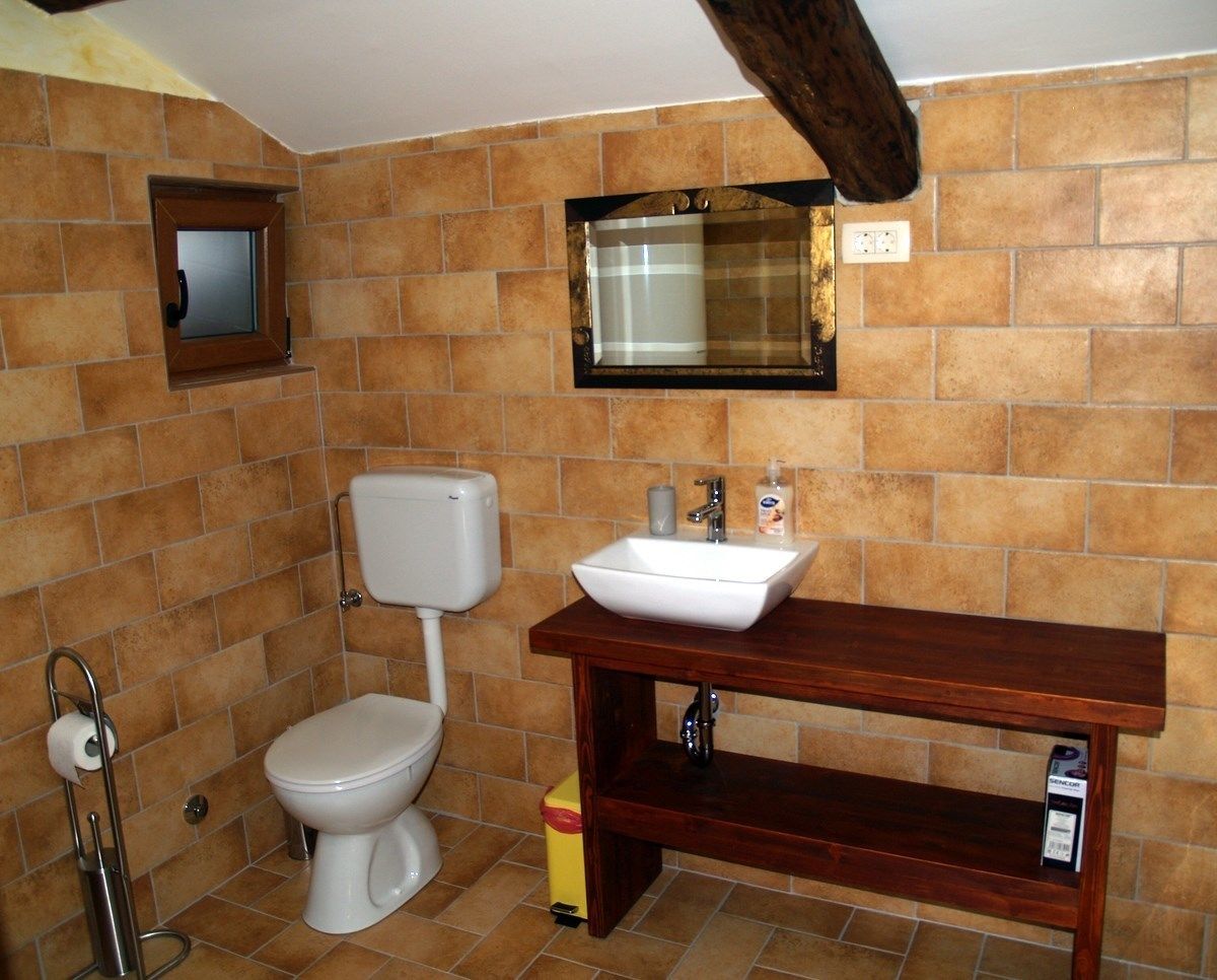 A bathroom with a toilet, sink, and mirror.