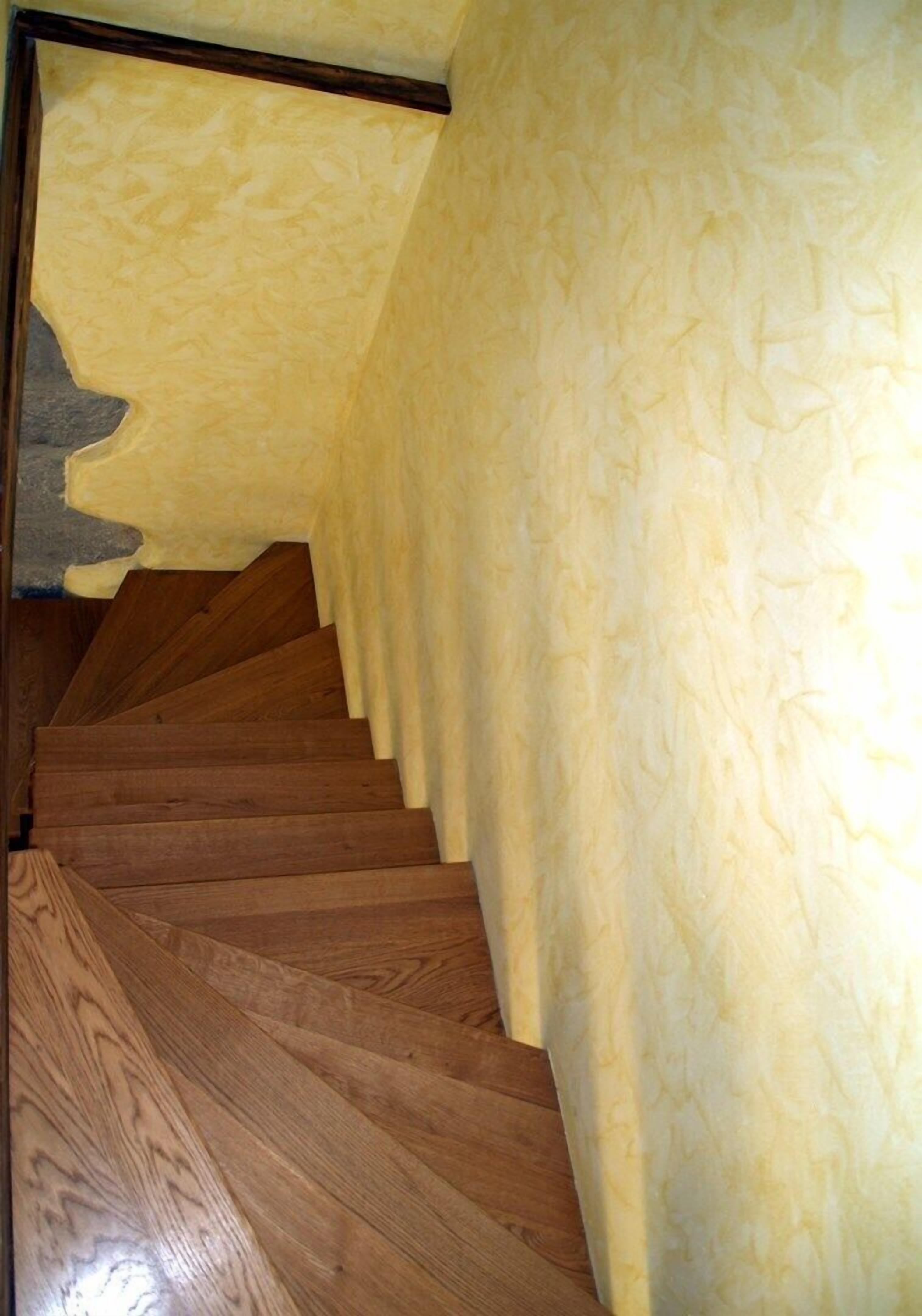 Een houten trap met een gestructureerde wand aan één kant.