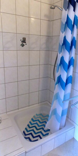 A shower area with a chevron-patterned shower curtain, a handheld showerhead, and a tiled wall. - Apartments Lalić (Vir)
