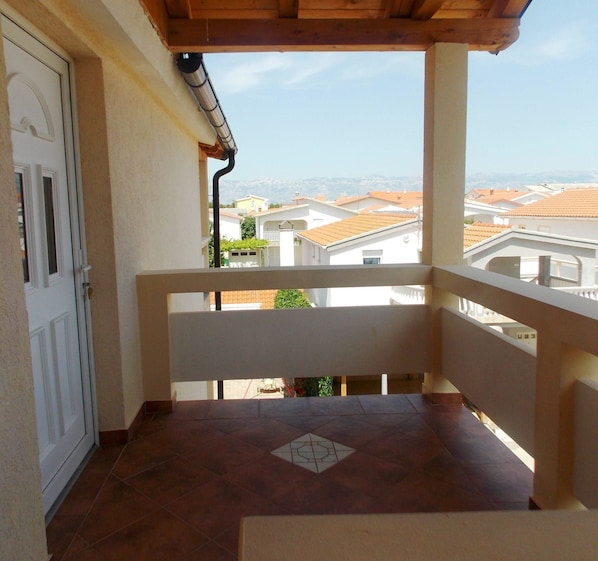 A balcony with a tiled floor, a white door, and a view of neighboring buildings. - Apartments Lalić (Vir)