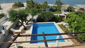 A swimming pool with a view of the sea, surrounded by greenery and a few parked cars. - Villa Sofija (Selca)
