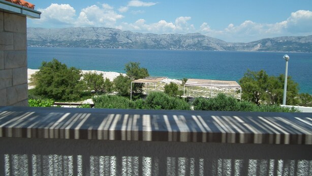 A coastal view with a clear sky, a mountain range in the background, and a building with a tiled roof. - Villa Sofija (Selca)