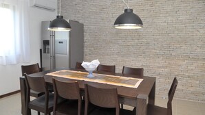 A dining area with a brick wall, a modern kitchen, and pendant lighting. - Villa Sofija (Selca)