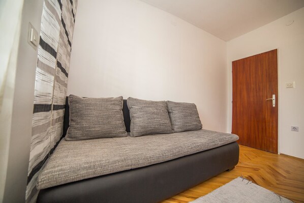 A modern living room with a sofa, a wooden door, and a patterned wall.