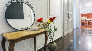 A hallway with a round mirror, a wooden console table with a vase of flowers, and a door with a white panel.