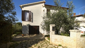 A two-story building with a stone facade, a small garden, and a paved entrance area. - Apartment Gasparini / Three Bedrooms (Pula)