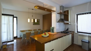 A modern kitchen with a central island, dining area, and a large window. - Apartment Gasparini / Three Bedrooms (Pula)
