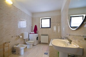 A bathroom with a toilet, bidet, washing machine, radiator, and a sink. - Apartment Gasparini / Three Bedrooms (Pula)